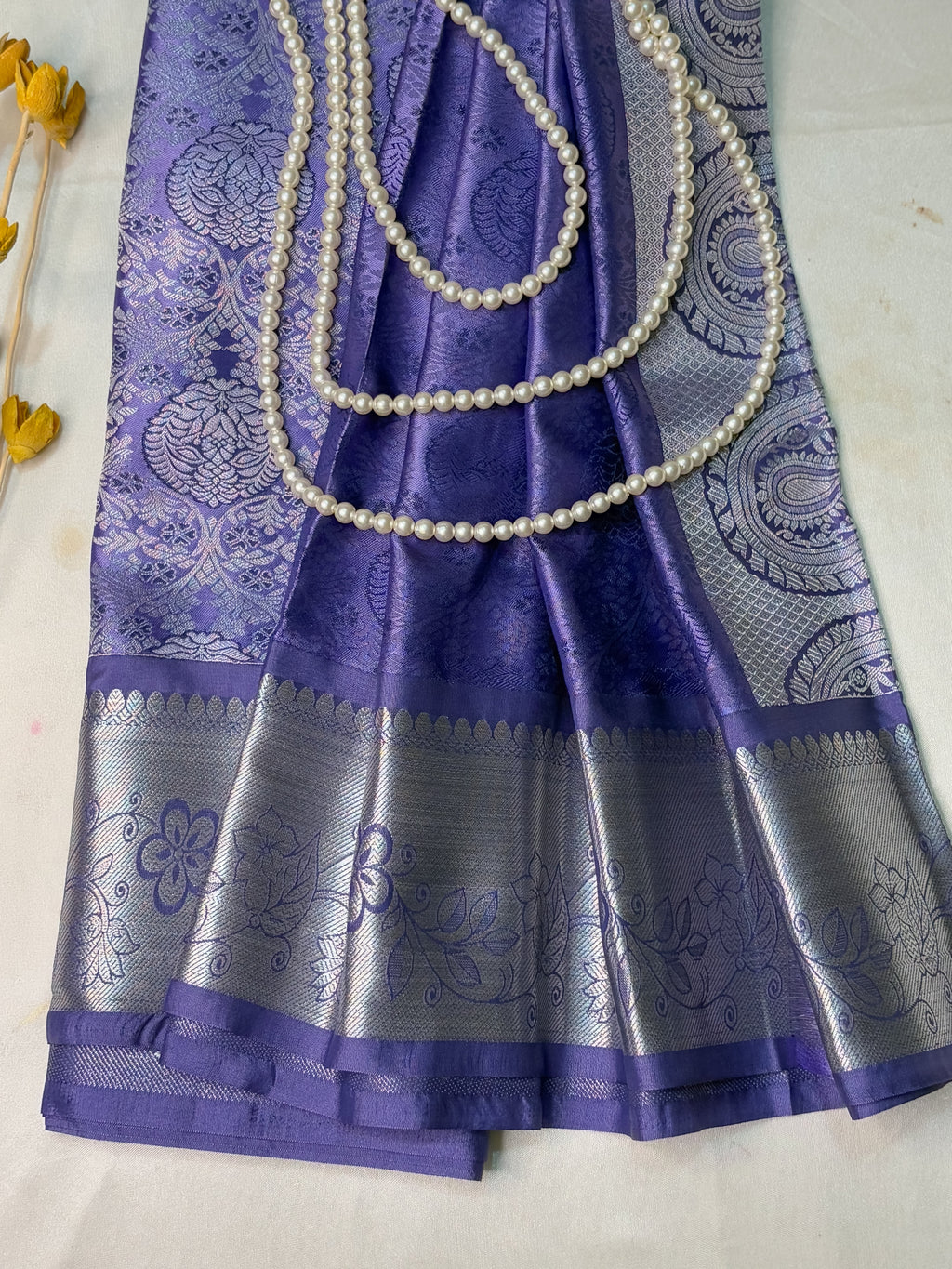 Purple saree with silver border and pearl border on a white background