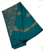 Teal saree with gold kolam patterns on a white background