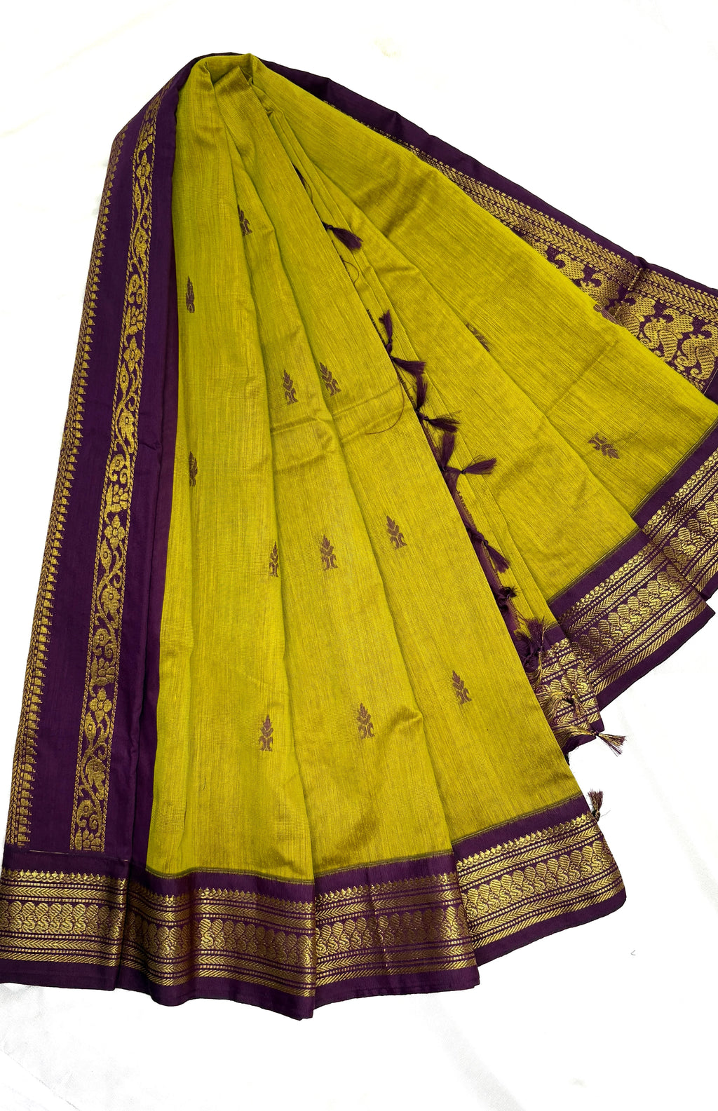 Green saree with purple border and gold embroidery on a white background