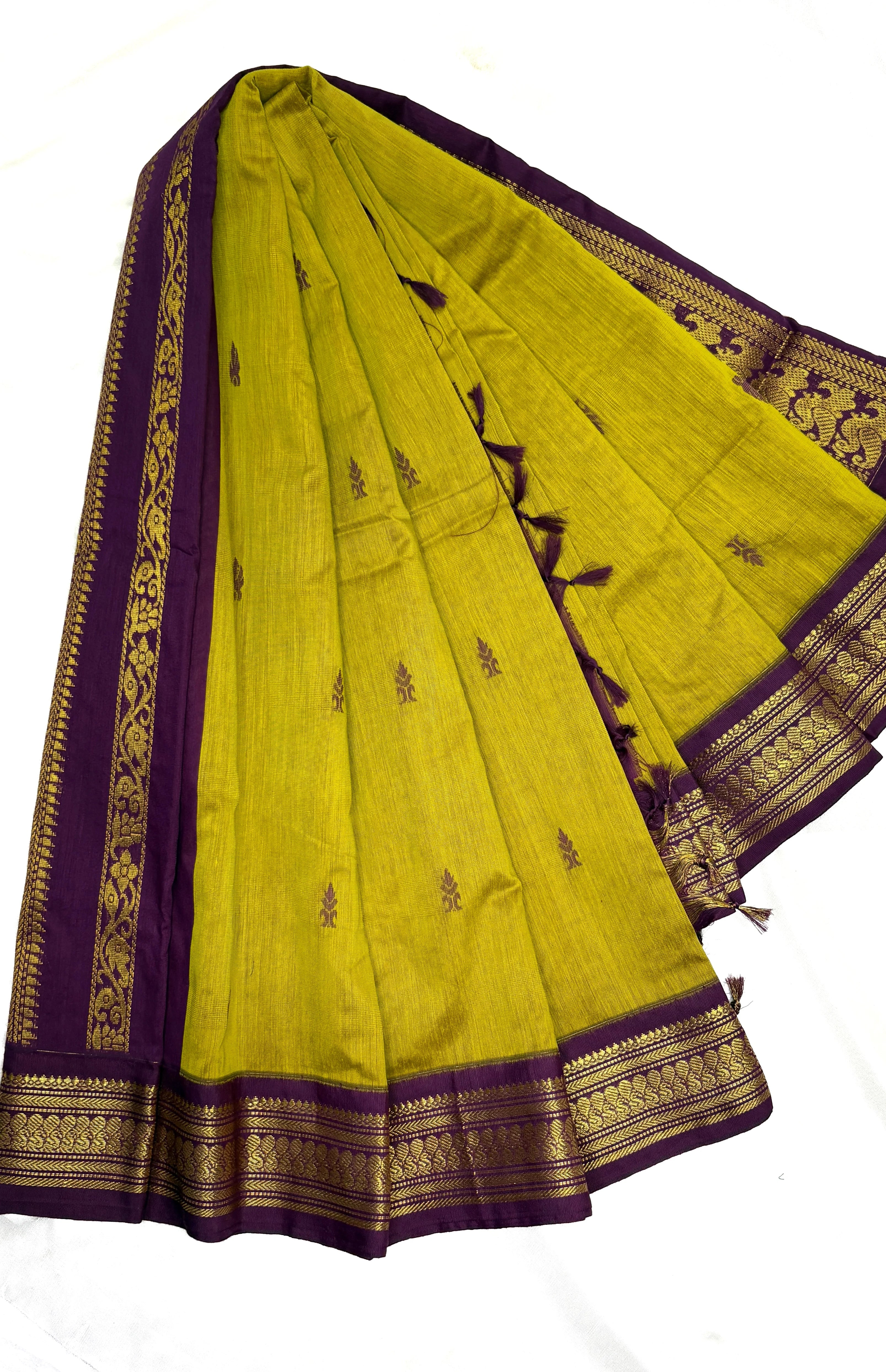 Green saree with purple border and gold embroidery on a white background