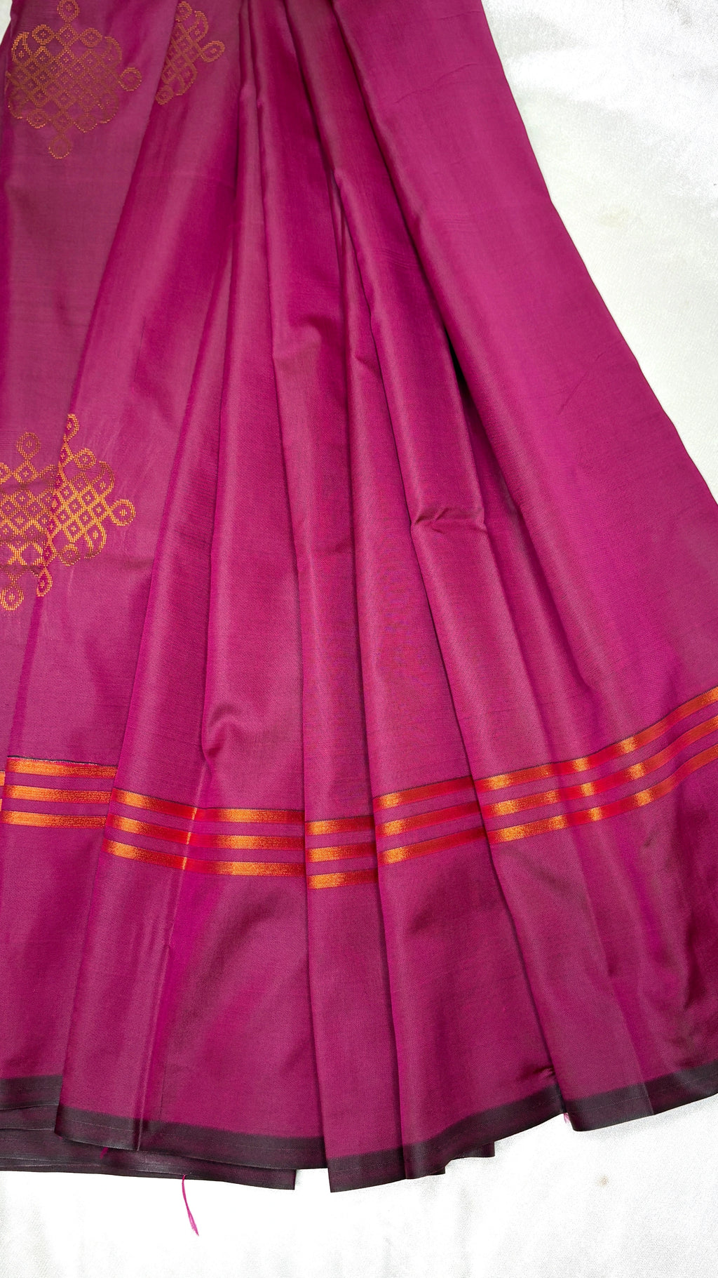 Pink saree with gold kolam patterns and border on a white background